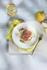 Fresh delicious salad with prosciutto, arugula with rose wine on light great marble background. Healthy diet concept. Italian cuisine. Vertical