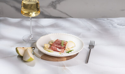 Fresh delicious salad with prosciutto, arugula with rose wine on light great marble background. Healthy diet concept. Italian cuisine. Vertical