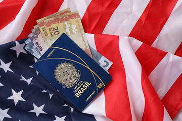 Blue Brazilian passport and money on United States national flag background close up. Tourism and...