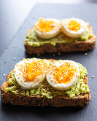 avocado toast topped with sliced boiled eggs and sesame seeds