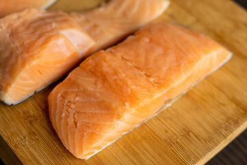  Close-up of raw, fresh salmon fillets arranged neatly on a wooden cutting board, showcasing their vibrant colors and textures