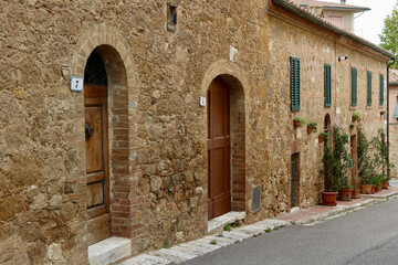 Fototapeta na wymiar Old street in the picturesque ancient town. San Quirico d'Orcia in Tuscany, Italy. 