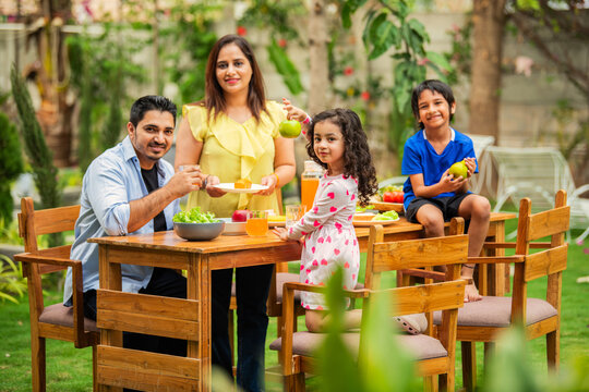 Indian couple and kids Enjoying Family Meal in the garden dining table