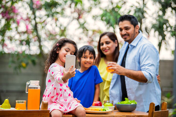 Indian couple and kids Enjoying Family Meal in the garden dining table