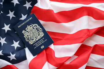 Blue British passport on United States national flag background close up. Tourism and diplomacy...