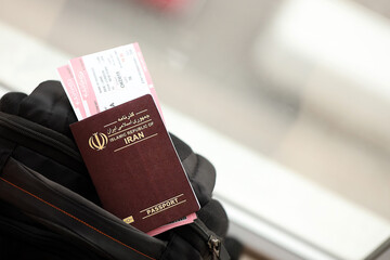 Red Islamic Republic of Iran passport with airline tickets on touristic backpack close up. Tourism and travel concept