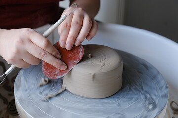 Close up of a person trimming and smoothing  ceramics on a pottery wheel.