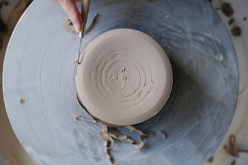 Top down of a person trimming and smoothing  ceramics on a pottery wheel.