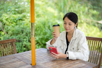 Woman drink of coffee and use smart phone at outdoor coffee shop - 762412053