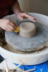 Person doing pottery on a pottery wheel in a studio.
