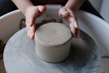 artist centering ceramics on a pottery wheel in a studio.