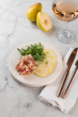Fresh delicious salad with prosciutto, arugula with rose wine on light great marble background. Healthy diet concept. Italian cuisine. Vertical