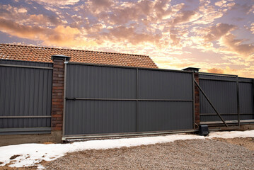 Automatic sliding metal gate on sunset