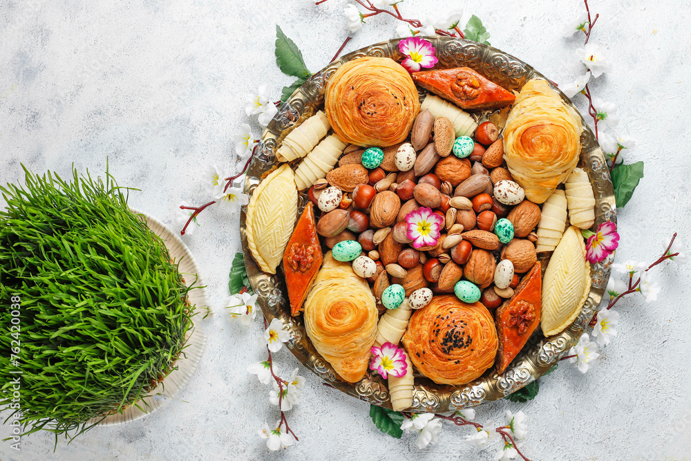 Sticker Traditional Azerbaijan holiday Novruz background with green semeni,traditional azerbaijan sweets,shekerbura,qogal,paxlava,mutaki and different nuts and sweets,top view,space for copy