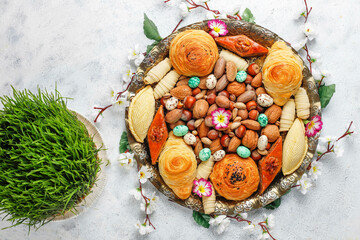 Fototapeta na wymiar Traditional Azerbaijan holiday Novruz background with green semeni,traditional azerbaijan sweets,shekerbura,qogal,paxlava,mutaki and different nuts and sweets,top view,space for copy