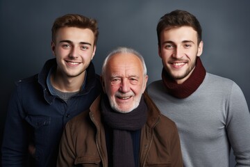 Three generations of men posing together with happy smiles on a dark background. Generations of Men Smiling Together
