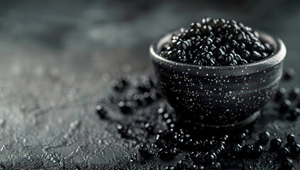 Black caviar in black ceramic bowl on dark background with copy space, luxurious taste concept. Premium sturgeon roe in a bowl on black background. Exclusive appetizer, source of omega-3 fatty acids - obrazy, fototapety, plakaty