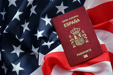Red Spanish passport of European Union on United States national flag background close up. Tourism...