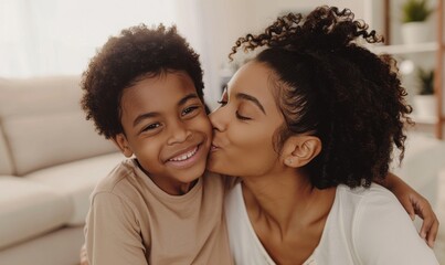   Young mother, son kisses mother's cheek white living room. 

 - obrazy, fototapety, plakaty