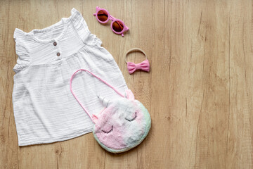 Set of baby girl dress and unicorn handbag. Kids wear flat lay