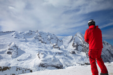 Fototapeta na wymiar rot gekleideter Skifahrer blickt auf die schneebedeckte Marmolada 