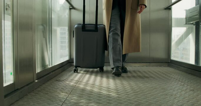 A woman with a suitcase gets out of the elevator, close-up of her legs, an unrecognizable person