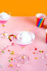 Caramel Milk shake cocktail with whipped cream and colored sweet candy cane lollipop for pink Birthday party
