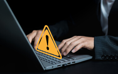 Adult man using computer laptop with triangle caution warning sign for notification error. Computer...