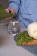 A woman's hand pours liquid chlorophyll into a glass, promoting vitamins for health, a healthy...