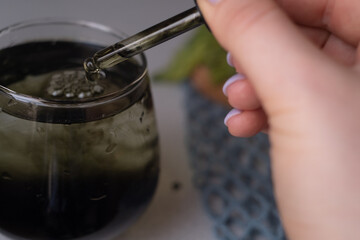A woman's hand pours liquid chlorophyll into a glass, promoting vitamins for health, a healthy lifestyle, combating vitamin deficiency, anemia, and morning rituals.