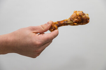 Caucasian man holds a crispy cooked a chicken leg
