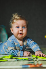 Fototapeta premium A 5-month-old baby boy lies on a rug and plays with silicone toys. Self-development of the child.