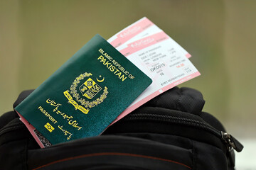 Green Islamic Republic of Pakistan passport with airline tickets on touristic backpack close up. Tourism and travel concept