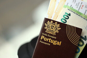 Naklejka premium Red Portugal passport of European Union with money and airline tickets on touristic backpack close up. Tourism and travel concept