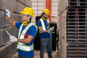Fototapeta na wymiar Caucasian engineers with yellow hardhat inspect steel bars with tablet in a factory