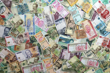 Many banknotes of different currency. Background of big amount of random money bills close up