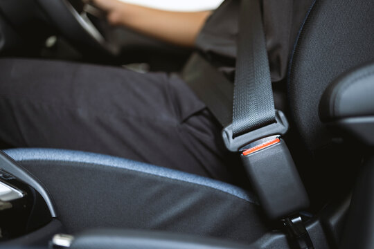 Close-up hand man driver fastens seat belt.