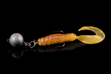 Soft fishing bait, silicone grub, with double hook and lead sinker, isolated on black background