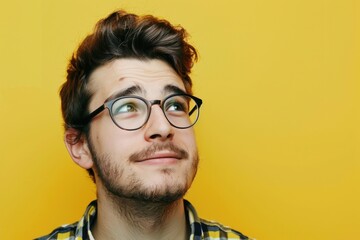 young man with glasses looking at yellow background stock photo