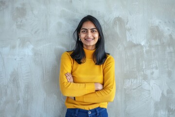 smiling woman with arms crossed wearing a yellow sweater and blue pants
