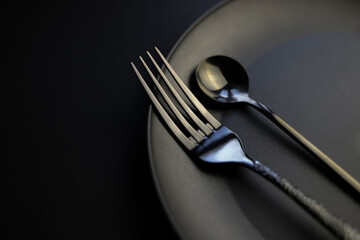 there is a fork and spoon on a black background and on a black plate