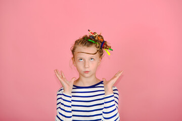 A girl with a funny hairstyle in a striped T-shirt touches her hair, is surprised and makes funny faces.