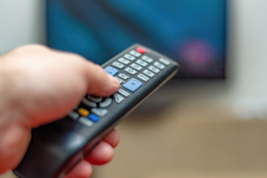 A person with a TV remote controls the remote control to switch channels to watch TV shows.