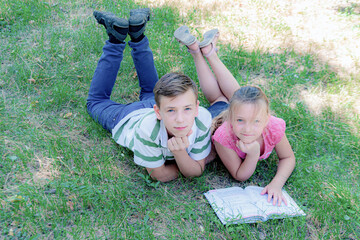 Boy with a girl doing homework on the grass in the park.
