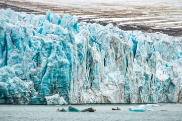 Huge glacier with small zodiac in Spitsbergen
