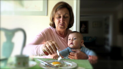 Grand-mother eating breakfast meal holding infant baby toddler grand-son