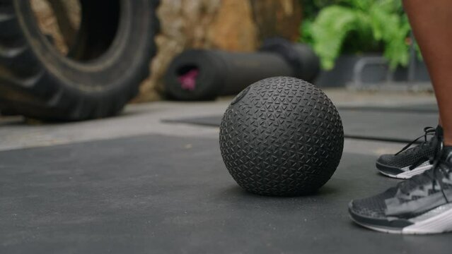 Active woman in fitness gear performs slam ball exercises at outdoor gym, surrounded by rich plants. Intense workout session focuses on strength, endurance, high-intensity functional training. Slowmo