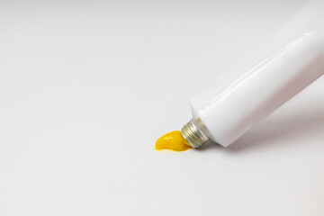 Opened ointment tube with yellow creme on the brigth background.Empty space