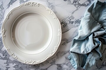 a large empty white plate next to a pale blue napkin on a marble surface - presentation