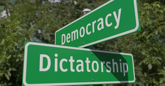 Pan of Democracy, Dictatorship Two Way Green Road Sign Along The Road.
